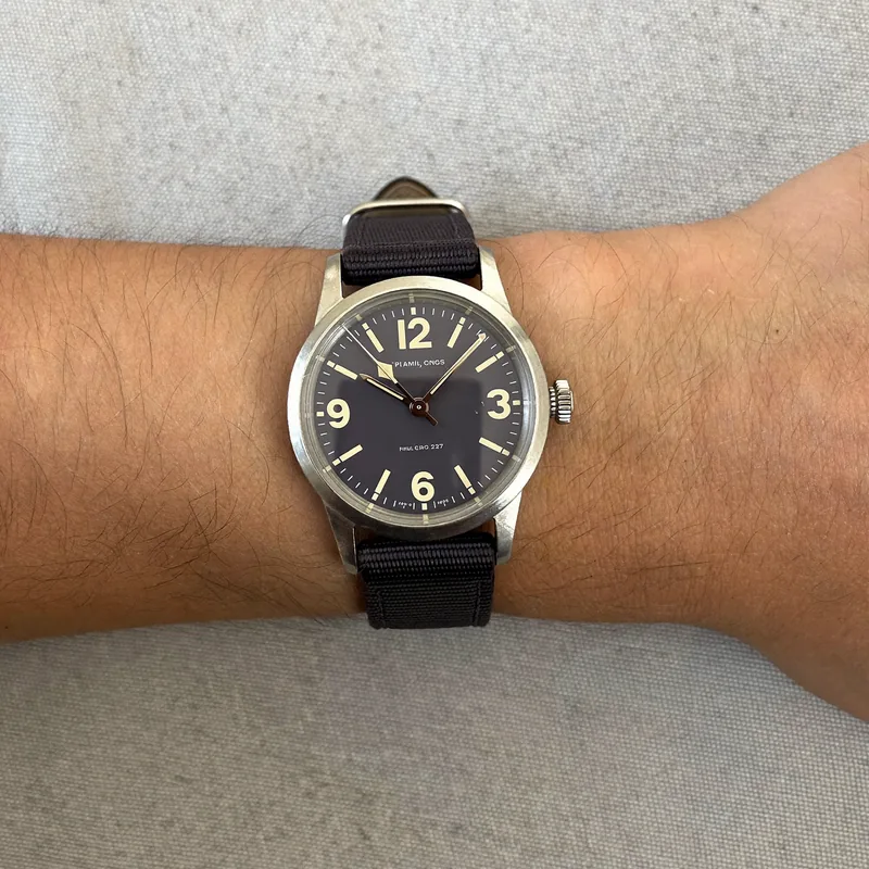 The spec reader: a medium wrist in a black strap, seen from above on a grey cloth