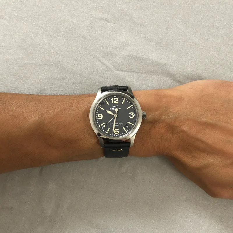 The first-watch buyer: a small wrist in a black strap, seen from above on a grey cloth