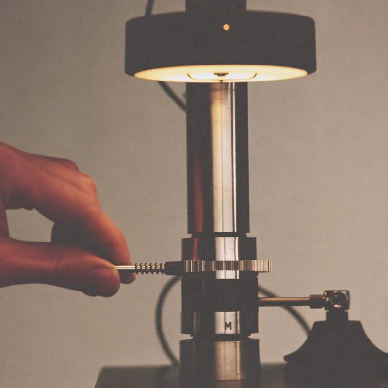 Regulating: a hand turning a regulating screw under a lamp
